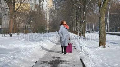 年轻迷人的女人，穿着温暖的外套，穿着五颜六色的针织围巾，在早期拉着她的紫罗兰色的大手提箱。